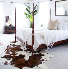 a bedroom with a four post bed and cow hide rug