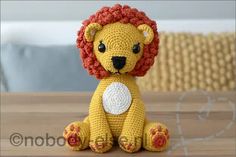 a crocheted lion sitting on top of a wooden table