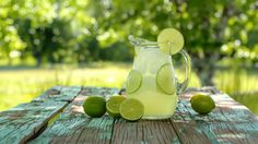 a pitcher filled with limeade sitting on top of a wooden table