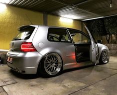 a silver car parked in a garage next to a yellow wall and some lights on