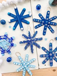 snowflakes and ornaments are displayed on a white board with blue stringing