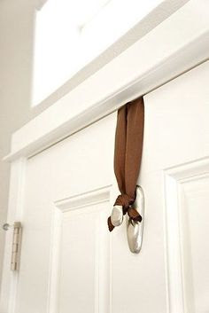 a pair of ballet shoes hanging on the front door with a brown ribbon tied to it