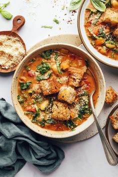 two bowls of soup with bread on the side