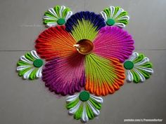 colorful paper fan shaped like a flower with a candle in it's center on the floor