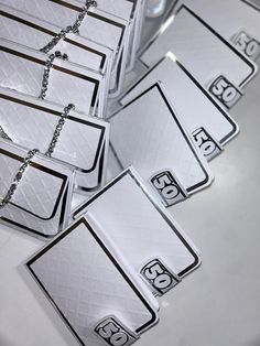 several silver tags with numbers on them are sitting on a counter top and have chains attached to them