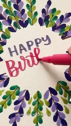 a hand holding a marker writing the word happy bride on a card with purple and green leaves