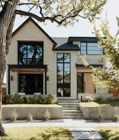 a large white brick house with black windows and steps leading up to the front door