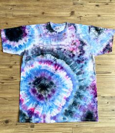 a blue and purple tie - dyed t - shirt sitting on top of a wooden floor