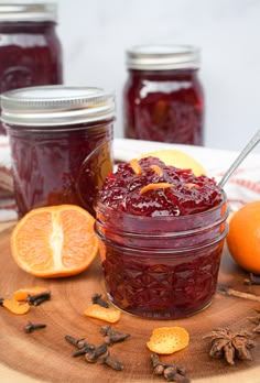 a jar filled with jam sitting on top of a table next to sliced oranges