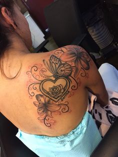 the back of a woman's shoulder with butterflies and a heart tattoo on it