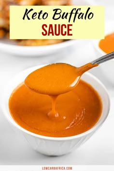 a spoon full of keto buffalo sauce in a white bowl with the words keto buffalo sauce above it