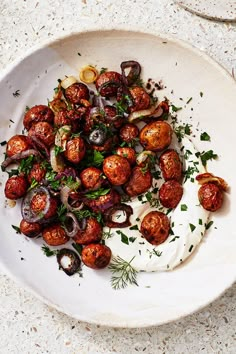 a white plate topped with meatballs and onions