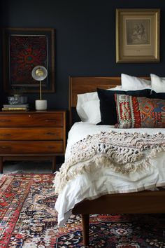 a bed with pillows and blankets on it in a room that has blue walls, wooden furniture, and rugs