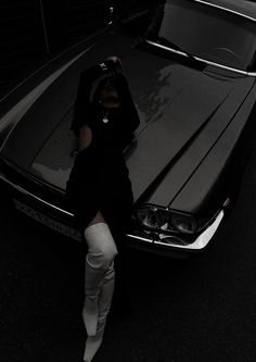 a woman leaning on the hood of a car