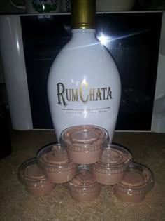 a white bottle sitting on top of a counter next to some brown cups and saucers