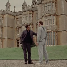 two men shaking hands in front of an old building