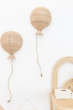 two rattan balloons hanging on the wall next to a wicker chair and table