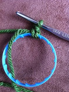 a pair of scissors are sitting on a piece of green yarn next to a blue ring