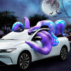 a white car with purple octopus decorations on it's hood in front of a full moon