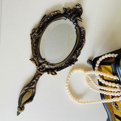 an ornate mirror with pearls hanging from it's sides next to a beaded necklace