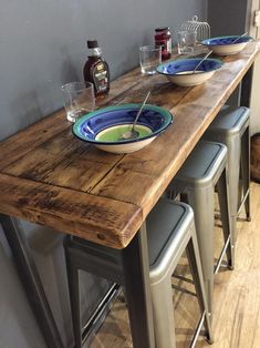 a table with three bowls on it and four barstools in front of it