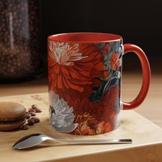 a red coffee mug sitting on top of a wooden cutting board next to a spoon