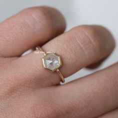 a woman's hand with a diamond ring on top of her finger and the other hand holding it