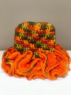 an orange and green knitted hat sitting on top of a white table