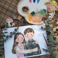 a drawing of a boy and girl on a table next to some paintbrushes