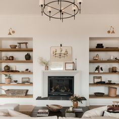 a living room filled with furniture and a fire place under a chandelier in front of a fireplace