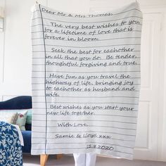 a blanket with writing on it in front of a blue chair and white wall behind it