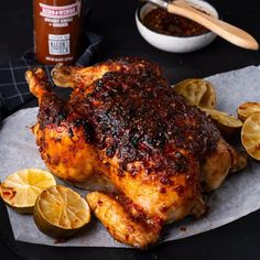 a roasted chicken with lemons and garlic on a plate next to some condiments