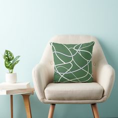 a green pillow sitting on top of a white chair next to a potted plant