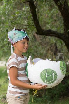 a young boy holding a paper mache in his hands