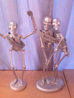 two skeleton figurines sitting on top of a wooden table next to each other