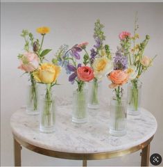 four vases with flowers are sitting on a marble table