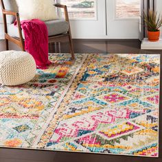 a colorful area rug with a chair and potted plant on the floor next to it