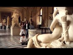 people are standing around in a museum with statues on either side of the room and one person kneeling down