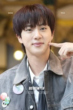 the young man is pointing to his left side with buttons on his jacket and tie