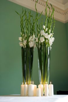 three vases with flowers and candles on a table