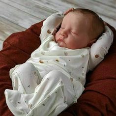 a newborn baby wrapped in a blanket is laying on a red bean bag with his head resting on the pillow