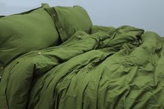 an unmade bed with green sheets and pillows