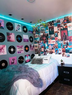 a bed with lots of records on the wall above it and a night stand next to it