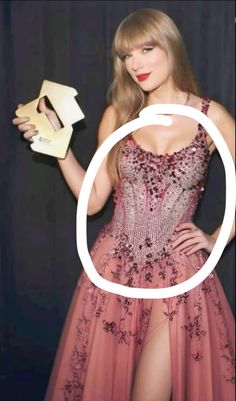 taylor swift wearing a pink dress and holding an object in front of her face with the letter o on it