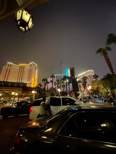 cars are parked on the street in front of hotels and palm trees at night time