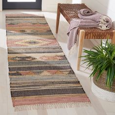 a large rug is sitting on the floor next to a chair and potted plant