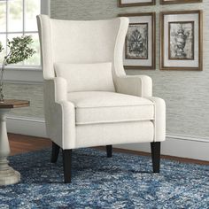 a white chair sitting on top of a blue rug next to a wall with pictures