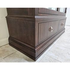 a large wooden dresser sitting on top of a tile floor next to a white wall