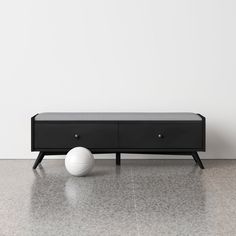 a white ball sitting on top of a black bench next to a wall and floor