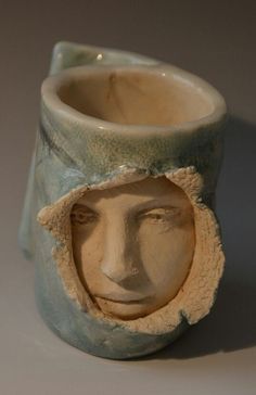 a ceramic vase with a face in the middle and a hole in the side to show it's inner workings